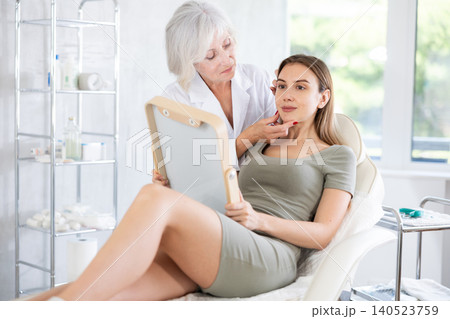 Cosmetologist with gloves preparing patient to skin care procedure in spa salon. Cosmetologist with gloves preparing patient to skin care procedure in spa salon. 140523759