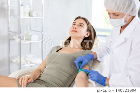 Elderly doctor drawing blood from young patient. Elderly doctor drawing blood from young patient. 140523904