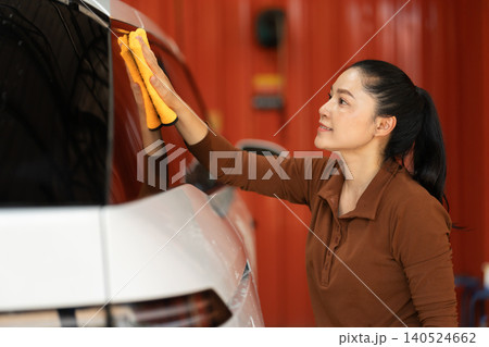 woman washing car with microfiber cloth in a self-service car wash station woman washing car with microfiber cloth in a self-service car wash station 140524662