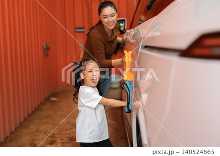 happy child girl with woman washing car with microfiber cloth in a self-service car wash station happy child girl with woman washing car with microfiber cloth in a self-service car wash station 140524665