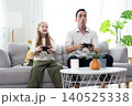 Father and daughter playing video games together at home. Happy family spending quality time, bonding, entertainment, and modern lifestyle in a cozy living room. 140525338