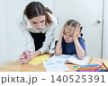 Teacher assisting young student with drawing and learning activity in classroom. Creative education, child development, personalized learning, and academic support concept. 140525391