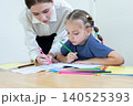 Teacher assisting young student with drawing and learning activity in classroom. Creative education, child development, personalized learning, and academic support concept. 140525393