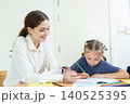 Teacher assisting young student with drawing and learning activity in classroom. Creative education, child development, personalized learning, and academic support concept. 140525395