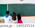 Boys and girls student writing on blank green chalkboard in classroom during lesson at school 140525514