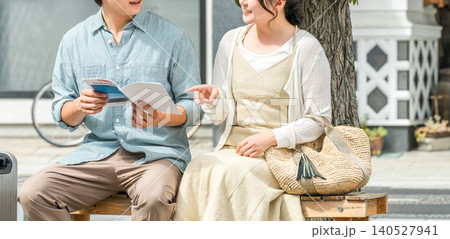 旅行先でガイドブックを見ながら会話する若い夫婦・カップル 旅行先でガイドブックを見ながら会話する若い夫婦・カップル 140527941