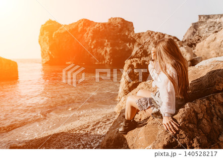 Woman sunset coast sitting on rocky cliffs overlooking a shimmering sea during golden hour to enjoy peaceful nature views Woman sunset coast sitting on rocky cliffs overlooking a shimmering sea during golden hour to enjoy peaceful nature views 140528217