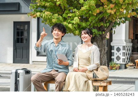 旅行先でガイドブックを見ながら会話する若い夫婦・カップル 旅行先でガイドブックを見ながら会話する若い夫婦・カップル 140528243