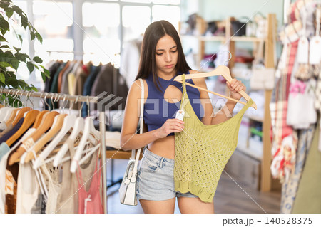 Young woman choosing top in clothing store 140528375