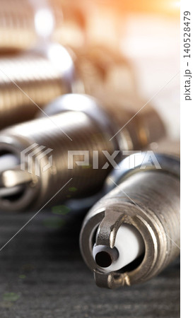 New spark plugs detail, engine component essential for combustion, power delivery of vehicle, close-up composition, car maintenance and repair equipment, bright warm light flare vertical photo 140528479