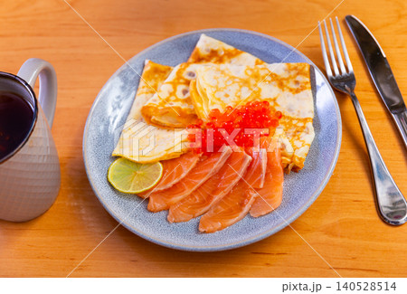 Thin pancakes with caviar and salmon on a plate 140528514