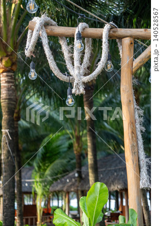 Rustic tropical resort decor with hanging vintage light bulbs and rope details surrounded by palm trees in Vietnam. Rustic tropical resort decor with hanging vintage light bulbs and rope details surrounded by palm trees in Vietnam. 140528567