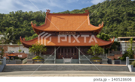 Magnificent Ho Chi Minh memorial temple with traditional double-tiered orange tiled roof and ornate wooden carvings, set against lush green hills in Vietnam. Magnificent Ho Chi Minh memorial temple with traditional double-tiered orange tiled roof and ornate wooden carvings, set against lush green hills in Vietnam. 140528606