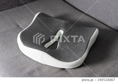 Modern orthopedic memory foam seat cushion, ergonomic design for coccyx and posture support, grey and white color, product photography 140528867