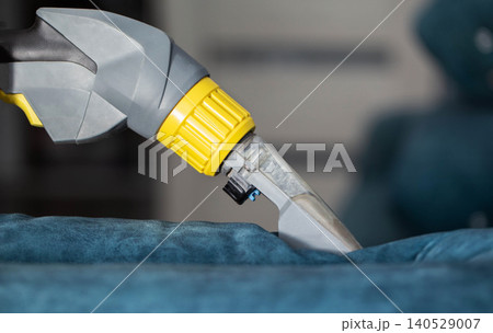 Detailed cleaning of a blue upholstery fabric using a specialized cleaning tool in an indoor setting Detailed cleaning of a blue upholstery fabric using a specialized cleaning tool in an indoor setting 140529007