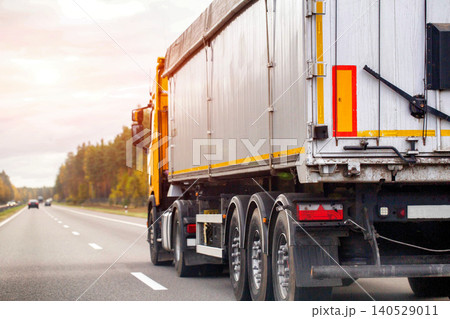 Large semi truck trailer transportation on asphalt highway road at sunset sky driving cargo delivery logistics freight industry commercial vehicle moving goods 140529011