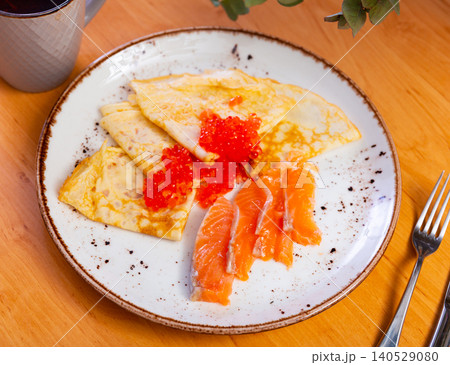 Thin pancakes with caviar and salmon on a plate 140529080