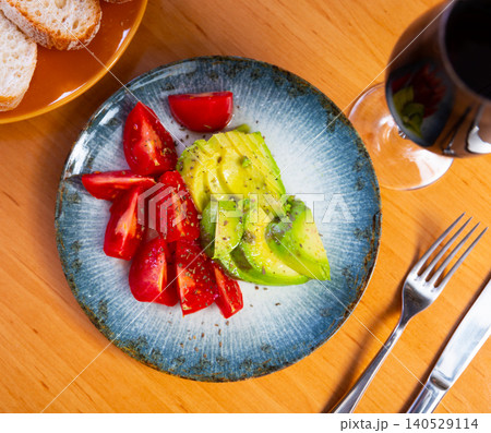 Sliced avocado and tomato on a plate top view Sliced avocado and tomato on a plate top view 140529114