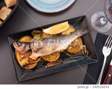 Fresh sea bass baked with herbs and potatoes. Fresh sea bass baked with herbs and potatoes. 140529243