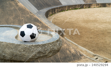 公園の砂のグラウンドにある丸い石の上の白黒サッカーボール 140529294