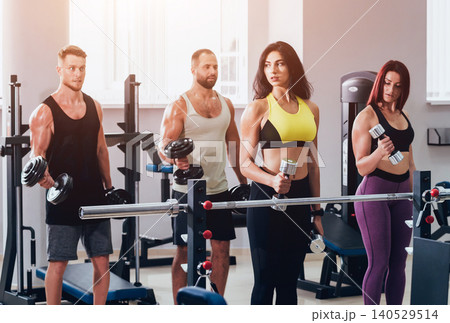 Group of athletic young peoples making exercise at the gym. Young men and women with muscular body. 140529514