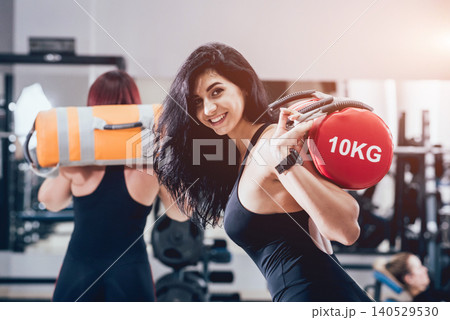 Athletic young women training with sandbags at gray background. Crossfit center Athletic young women training with sandbags at gray background. Crossfit center 140529530