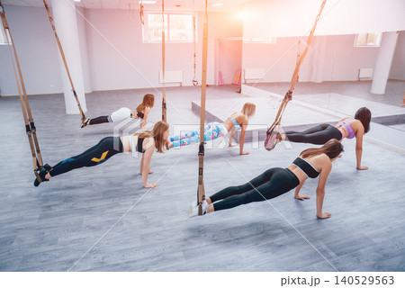 Beautiful young sports women are working out with TRX in gym Beautiful young sports women are working out with TRX in gym 140529563