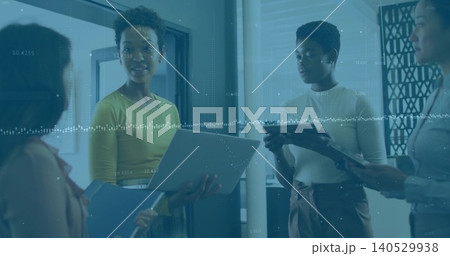 Holding laptop and blue folder, woman in chartreuse top leading huddle at office with data overlay 140529938
