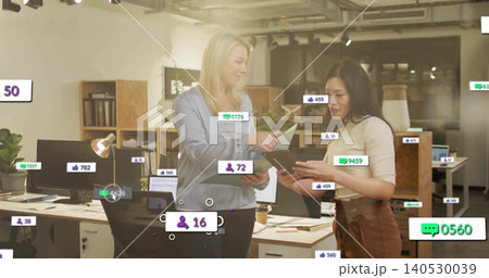 Discussing two coworkers in blouses reviewing tablet and papers at office desk with social overlays Discussing two coworkers in blouses reviewing tablet and papers at office desk with social overlays 140530039