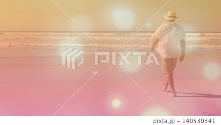 Walking middle-aged man leaving prints on wet sand at shoreline, with straw hat, shorts, copy space Walking middle-aged man leaving prints on wet sand at shoreline, with straw hat, shorts, copy space 140530341