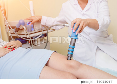 Shock wave therapy. The magnetic field, rehabilitation. Physiotherapist doctor performs surgery on a patient's knee 140530411