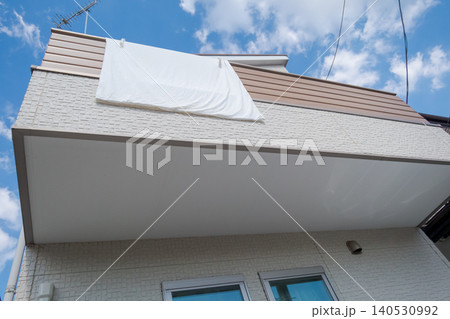 一戸建てのベランダに洗濯した布団シーツを干す 一戸建てのベランダに洗濯した布団シーツを干す 140530992