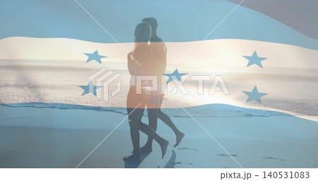 Walking couple in swimwear leaving prints on wet sand, faint flag overlay showing five blue stars Walking couple in swimwear leaving prints on wet sand, faint flag overlay showing five blue stars 140531083