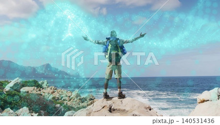 Standing adult male hiker facing open sea on rocky outcrop, wearing backpack, cap, boots, nebula Standing adult male hiker facing open sea on rocky outcrop, wearing backpack, cap, boots, nebula 140531436