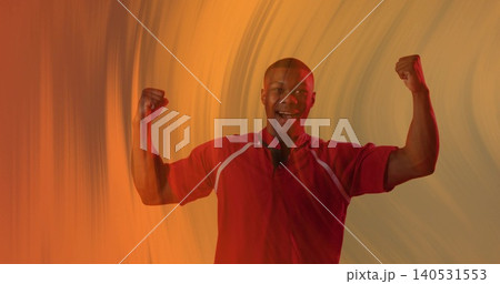 Smiling adult man flexing double biceps pose in studio, wearing red athletic shirt, warm lighting Smiling adult man flexing double biceps pose in studio, wearing red athletic shirt, warm lighting 140531553