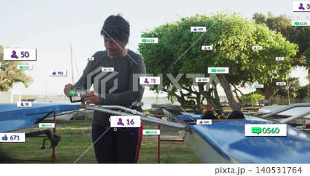 Checking senior in athletic top viewing phone near rigging at launch, blue shell with overlays 140531764