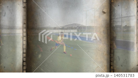 Practicing teen athlete dribbling orange ball on turf, in yellow jersey and socks holding stick Practicing teen athlete dribbling orange ball on turf, in yellow jersey and socks holding stick 140531783