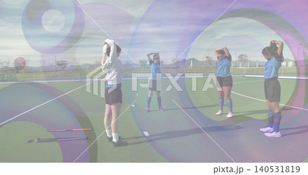 Stretching four players in blue shirts raising hands on turf, with two field hockey sticks 140531819