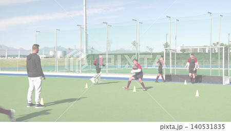Running male players in maroon-and-black tops practicing drills on synthetic turf with yellow cones 140531835