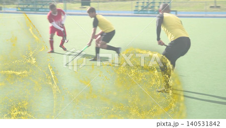 Controlling central player in yellow bib bending on turf with hockey stick, red kit, yellow overlay Controlling central player in yellow bib bending on turf with hockey stick, red kit, yellow overlay 140531842