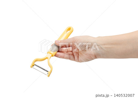 Woman's hand holding a vegetable peeler on the white background. Woman's hand holding a vegetable peeler on the white background. 140532007