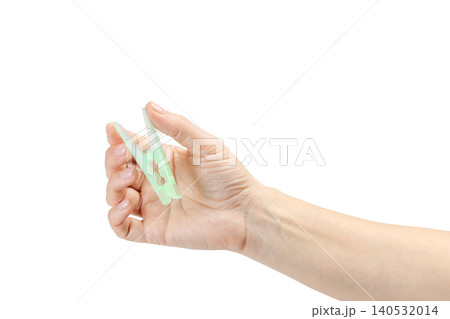 Woman's hand holding a clothespin on a white background 140532014