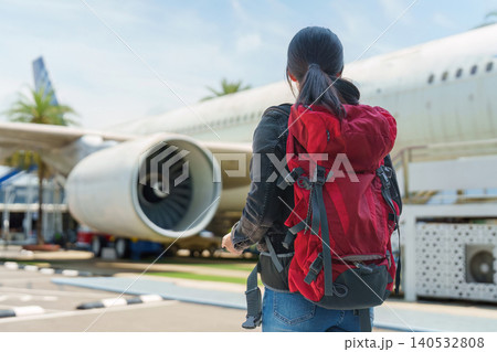Asian woman with backpack looking at airplane at airport Asian woman with backpack looking at airplane at airport 140532808
