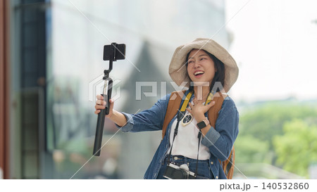 Asian woman vlogging with smartphone on selfie stick for travel content Asian woman vlogging with smartphone on selfie stick for travel content 140532860