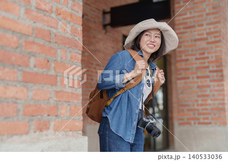 Happy Asian woman traveler exploring urban street with camera Happy Asian woman traveler exploring urban street with camera 140533036