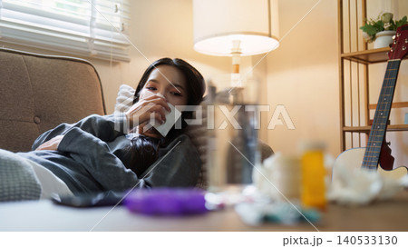 Asian woman resting on couch feeling sick with medicine in foreground 140533130