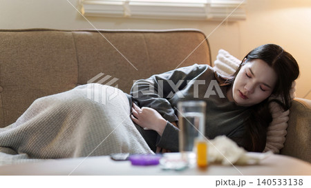 Asian woman suffering from stomach pain lying on sofa at home Asian woman suffering from stomach pain lying on sofa at home 140533138