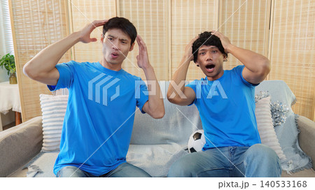 Asian and Southeast Asian men reacting with disappointment to football game Asian and Southeast Asian men reacting with disappointment to football game 140533168
