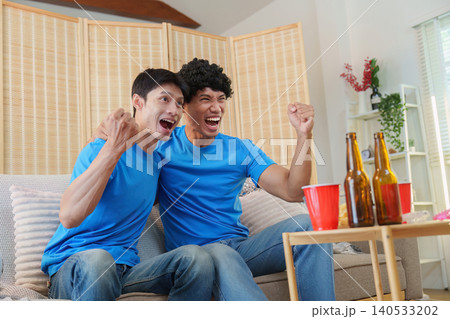 Excited Asian men cheering watching sports game at home Excited Asian men cheering watching sports game at home 140533202