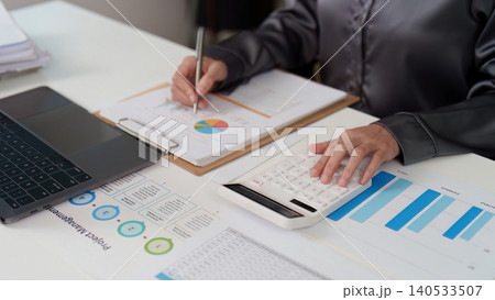 Person calculating finances with calculator and laptop on desk Person calculating finances with calculator and laptop on desk 140533507